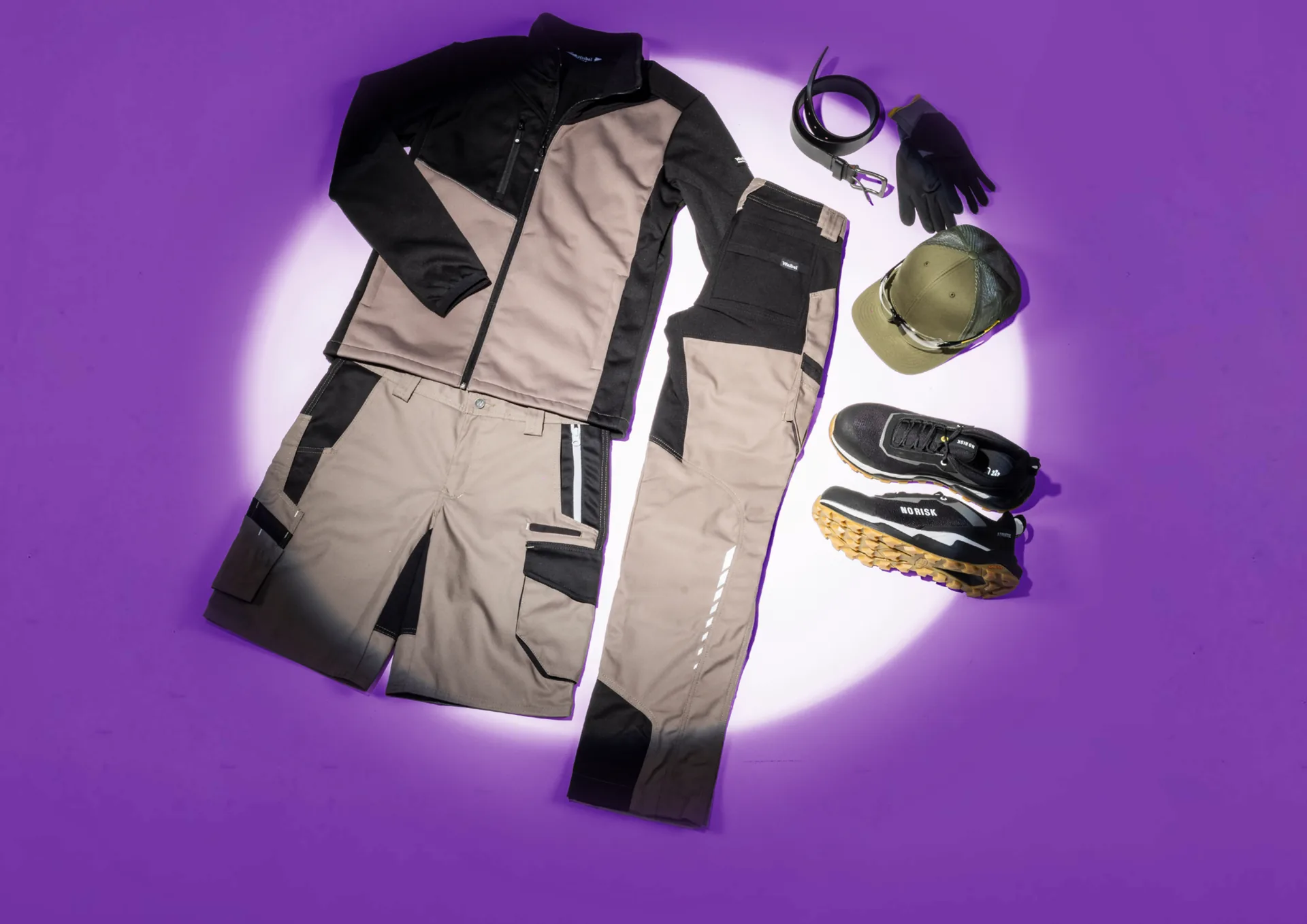 Komplettes Workwear-Outfit im Lichtspot: Jacke, Hose, Cap, Handschuhe und Schuhe