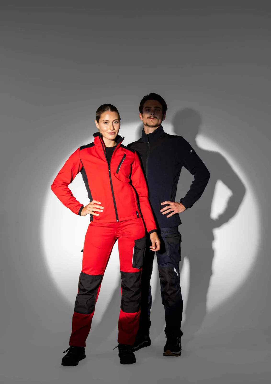 Frau in roter und Mann in dunkler Workwear im grauen Lichtspot